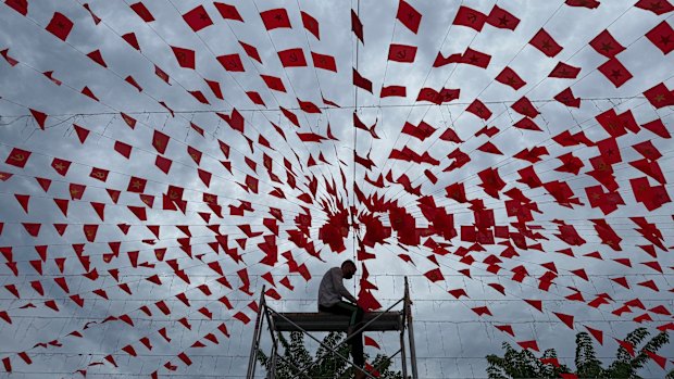 A man hangs up flags in Hanoi in preparation for Vietnam’s national day under a cloudy sky caused by Typhoon Kajiki on Monday.