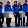 Police officers carry the coffin of an Italian teenager killed in the Swiss fire on to a plane at Sion airport.