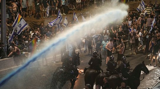 Riot police tries to clear demonstrators with a water cannon during a protest against plans by Netanyahu’s government to overhaul the judicial system, in Tel Aviv.