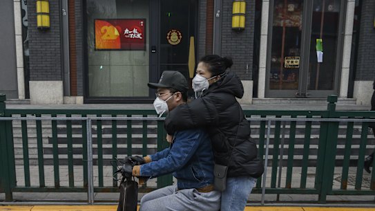 A Chinese couple wear protective masks as they ride a scooter on February 20, 2020 in Beijing, China.