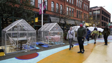 People walk by outdoor plastic dining bubbles on Fulton Market in Chicago.