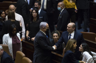 New Israeli Prime Minister Naftali Bennett shakes hands with outgoing Israeli Prime Minister Benjamin Netanyahu after parliament voted to approve the new government on Sunday.