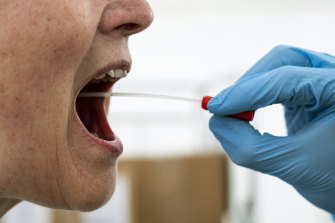 A medical worker performs a mouth swab on a patient to test for COVID-19 in a tent extension of the  Rigshospitalet Hospital in Copenhagen, Denmark.