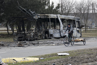 A woman rides past a burnt bus in Mariupol, Ukraine.
