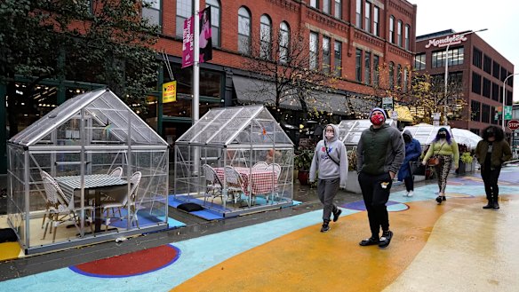 People walk by outdoor plastic dining bubbles on Fulton Market in Chicago.