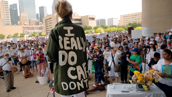 Actress and activist Cheryl Allison wears a "I Really DO Care, Don't U" green jacket as she speaks during the Keep Families Together rally at Dallas City Hall  on Saturday.