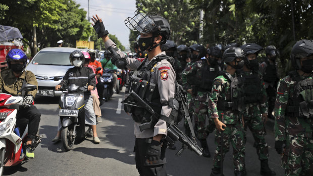 A police officer directs traffic as soldiers patrol the area near the court in Jakarta.