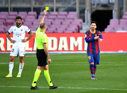 Lionel Messi of Barcelona is shown a yellow card after removing his shirt.