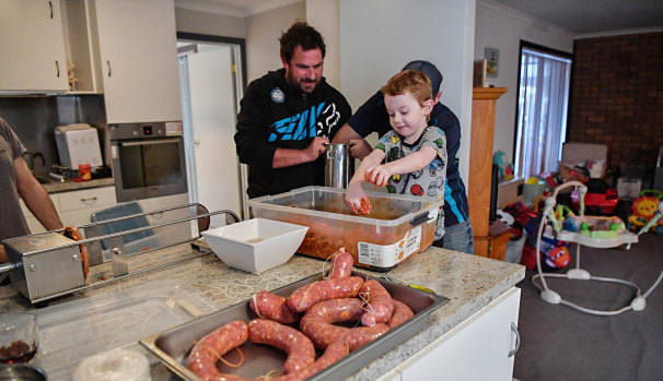 Five-year-old Phoenix Napoli, Steven Napoli (behind) and family friend Michael Cini making salami.