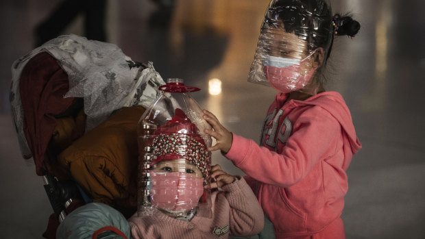 Chinese children wear plastic bottles as protective masks while waiting to check in to a flight in Beijing.