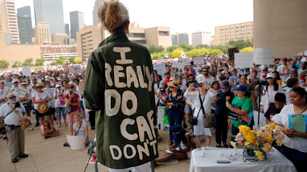 Actress and activist Cheryl Allison wears a "I Really DO Care, Don't U" green jacket as she speaks during the Keep Families Together rally at Dallas City Hall  on Saturday.