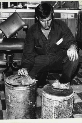 Detective N. Raward examines in the CIB laboratory two petrol drums found in the foyer of Brisbane Whiskey Au Go Go. March 9, 1973