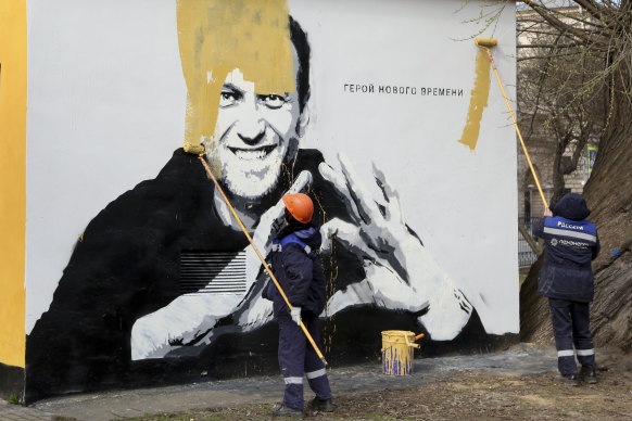 A municipal worker in St Petersburg paints over a mural of imprisoned opposition leader Alexei Navalny, in April.