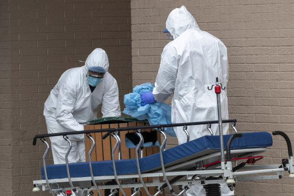 Medical personnel remove their protective gear after transporting bodies from the Wyckoff Heights Medical Centre in Brooklyn.