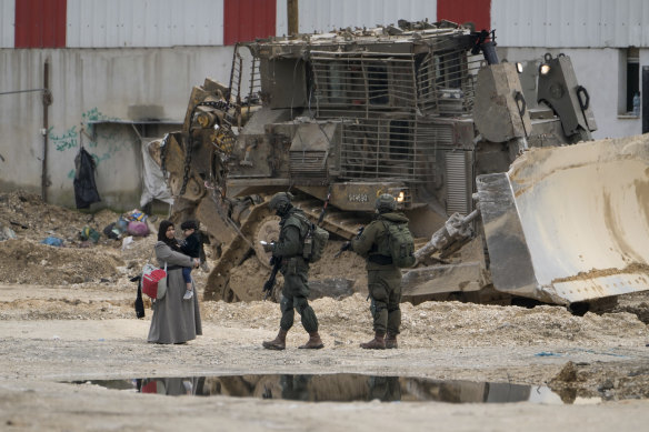 Israeli soldiers check the IDs of Palestinians in the West Bank refugee camp of Nur Shams.