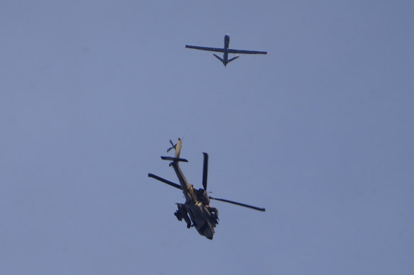 An Israeli military Apache helicopter and a drone fly close to the Gaza Strip, as seen from southern Israel.