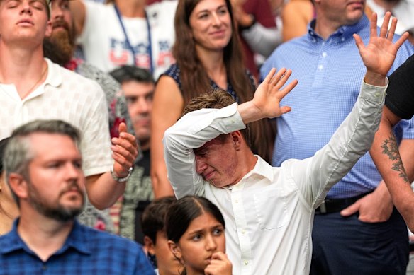A man in the crowd raises his arms.