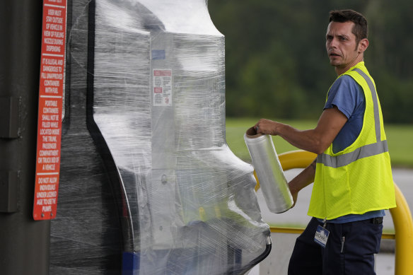 A petrol station employee wraps fuel pumps ahead of hurricane Helene.