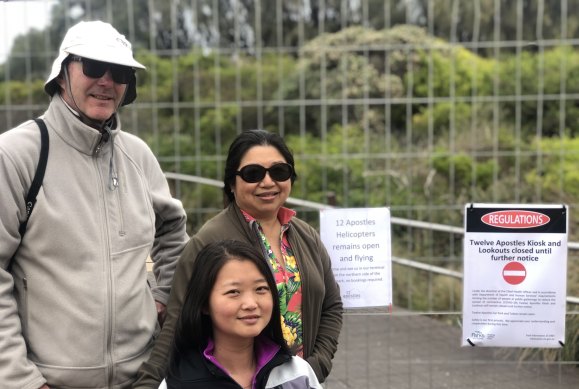Andrew Dawson with wife Debbie Ng (rear) and sister-in-law Kate Zhong, at the fence preventing access to the Twelve Apostles viewing platforms on Sunday. 