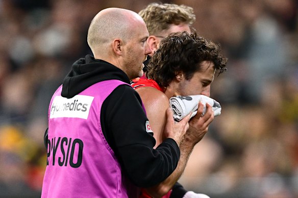 Andrew McGrath of the Bombers is helped from the ground by trainers.