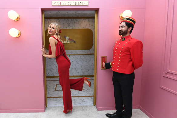 Melbourne Cup Carnival ambassador Tegan Martin tries out the elevator-inspired secret door at Mumm.