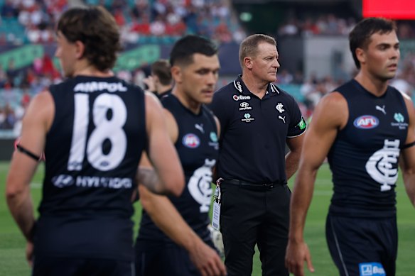Michael Voss has a new look group in his care as Ben Ainsworth (left) and Campbell Chesser (right) leave the huddle against the Swans.