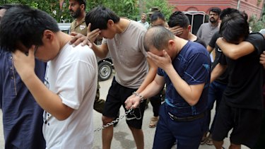 Detained Chinese nationals, accused of luring Pakistani women into fake marriages, are escorted to court in Lahore, Pakistan.