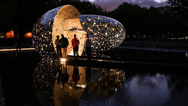 Visitors viewing Lindy Lee’s Ouroboros at night.