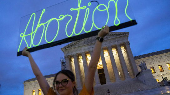 An activist marks the first anniversary of the Supreme Court’s decision that overturned Roe v Wade, by displaying a neon sign in support of abortion access in front of the US Supreme Court.