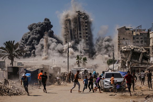 Palestinians run for cover during an Israeli airstrike on a high-rise building in Gaza City.