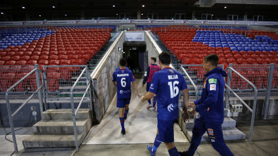 Newcastle Jets players leave an empty McDonald Jones Stadium after the last - and probably final - game of the A-League season.