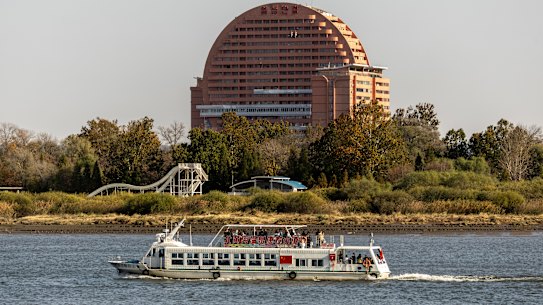 A river cruise takes Chinese tourists past the Sun building and waterslide park in the North Korean city of Sinuiju.