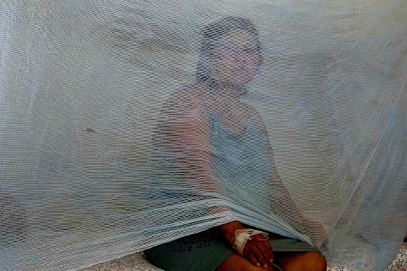 Jenny Chiroque, who suffering dengue, sits on a bed with netting at La Merced Hospital in Paita, Peru.