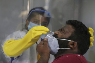 A health care worker takes a nasal swab sample to test for COVID-19 in Hyderabad, India.
