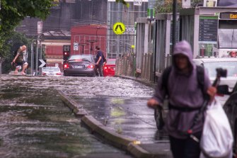 Pedestrians navigate rain-soaked streets in Carlton on Friday afternoon.