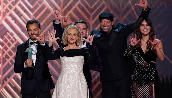 CODA’s actors accept the award for outstanding performance by a cast in a motion picture – signing “I love you” – at the Screen Actors Guild Awards.