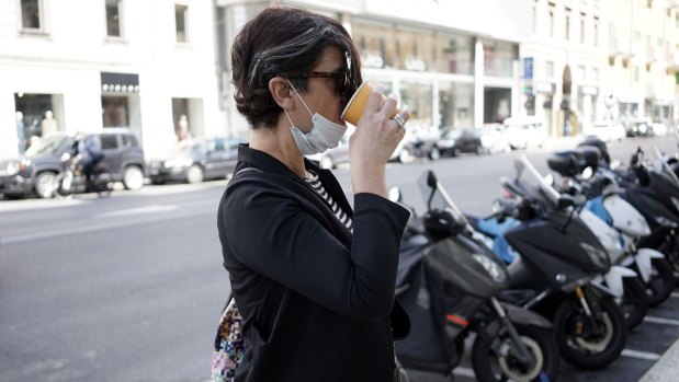 A woman drinks a cappuccino on the street in Milan, Italy. Italy was the first country to impose a nationwide lockdown to stem the transmission of the coronavirus.