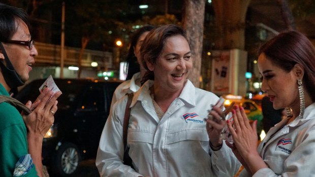 Pauline Ngarmpring (centre) and Chakkarin Singhanutta (right) talk to a passerby during a campaign walk in the heart of Bangkok.