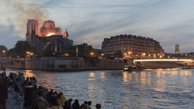 People watch as fire and smoke rise from a fire at Notre-Dame Cathedral in Paris, France.