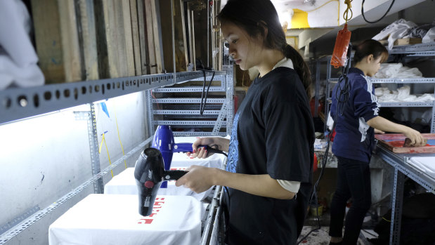 Staff at Thanh’s Hanoi workshop drying just-printed T-shirts with hairdryers on Tuesday.