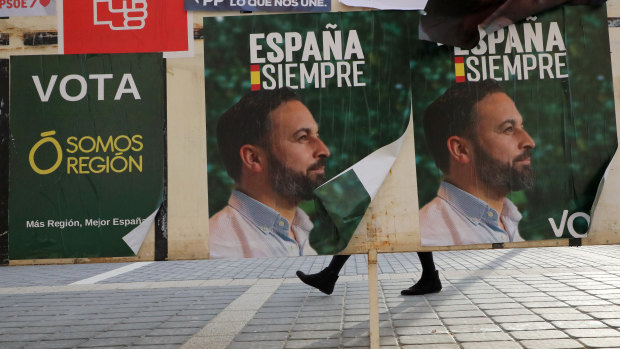 A woman walks past banners for Spain's far-right Vox party that proclaim: "Spain Forever."