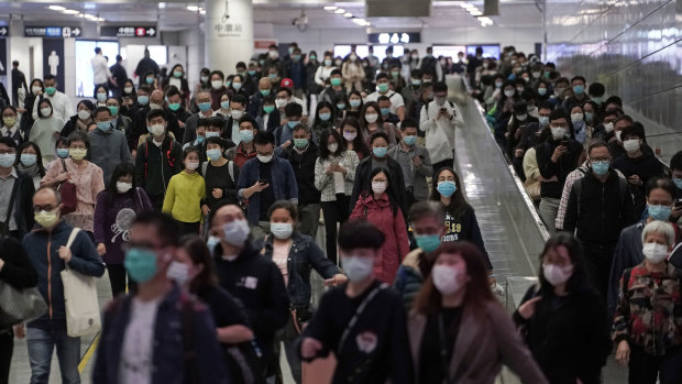 Commuters wear face masks as a precaution against the COVID-19 illness inside a subway station during rush hour in Hong Kong.