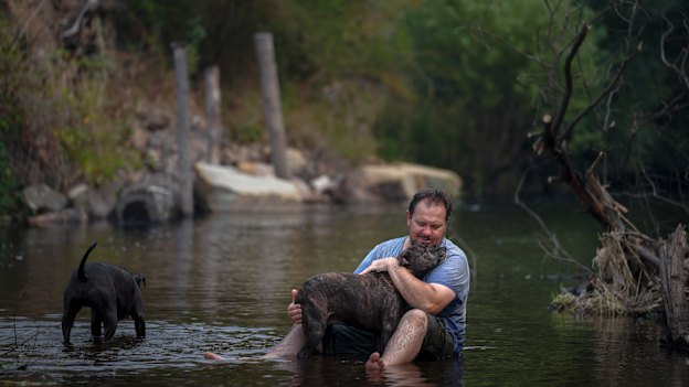 Aaron Hampton from Cudgewa with his dogs Mishka and Dobbie cools down in the river next to the Nariel Creek Folk Festival camp site. 