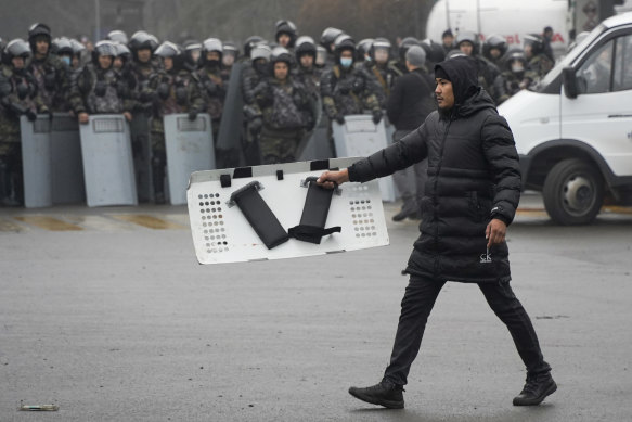 A demonstrator carries a police shield in front of police line during a protest in Almaty, Kazakhstan last week. 