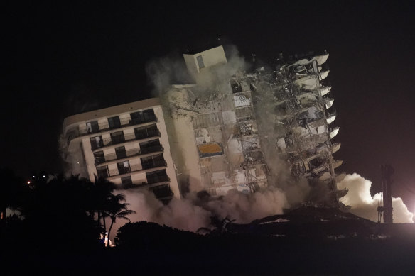 The damaged remaining structure at the Champlain Towers South building collapses in a controlled demolition late on Sunday, US time.