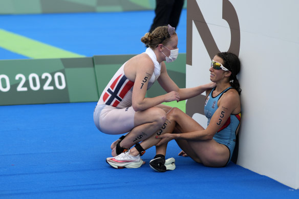 Claire Michel of Belgium is assisted by Lotte Miller of Norway after the finish of the women’s individual triathlon.