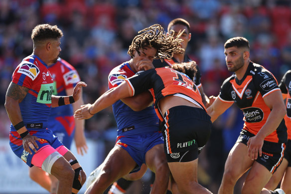 Knights winger Dominic Young is tackled by the Tigers during the round two match at McDonald Jones Stadium.