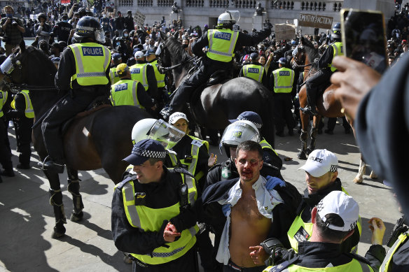 A wounded member of a far-right group is escorted away by British police as they try to contain a protest at Trafalgar Square in central London on Saturday, June 13.