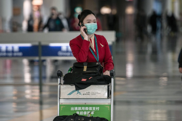 A Cathay Pacific employee pushes a luggage cart through Hong Kong International Airport.