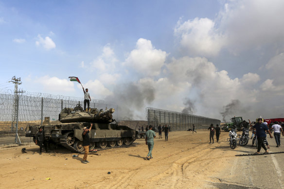 Palestinians on a destroyed Israeli tank at the Gaza Strip fence east of Khan Younis on October 7.